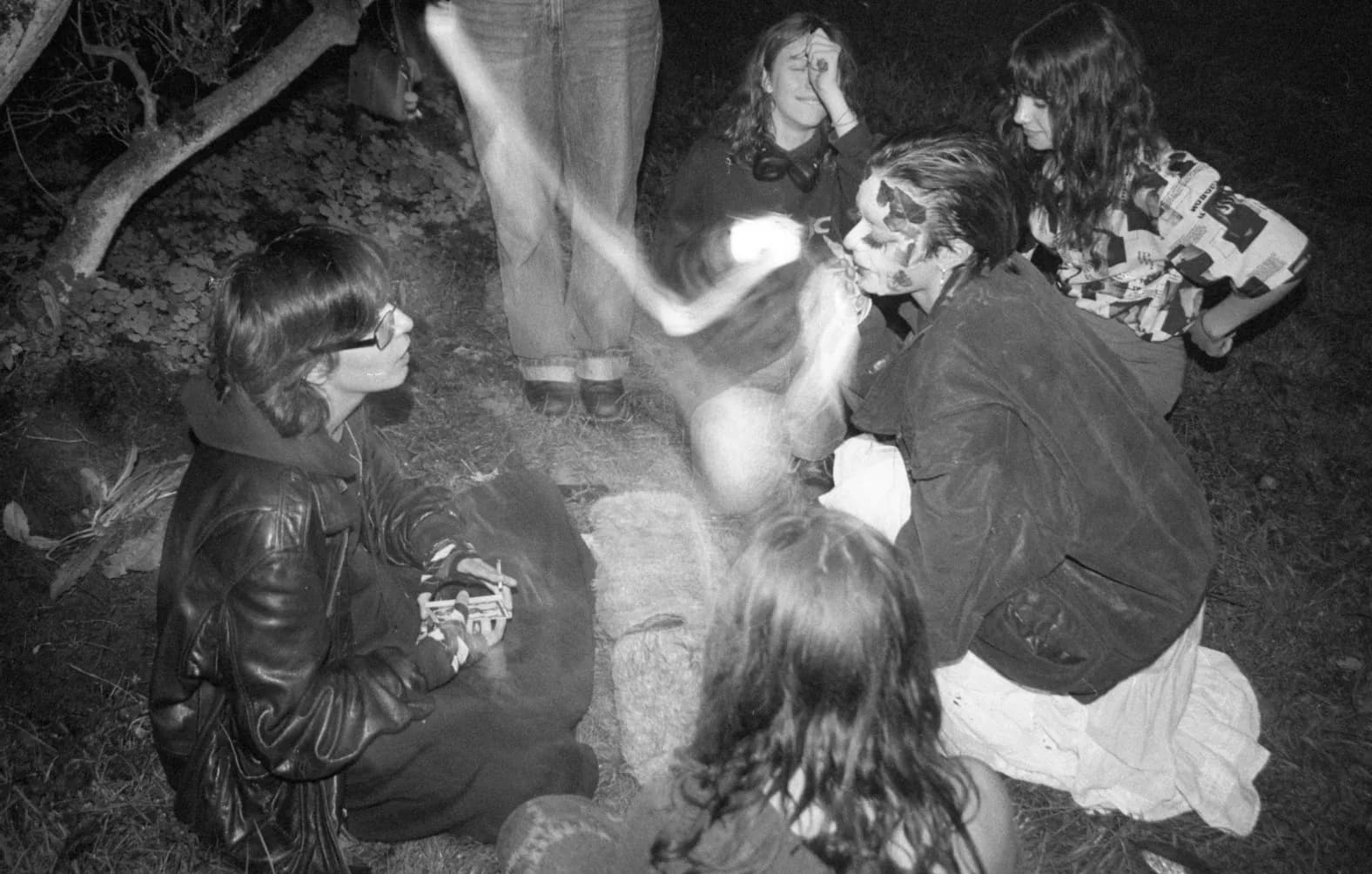 A group sitting in the grass at night, lit by flash, black and white